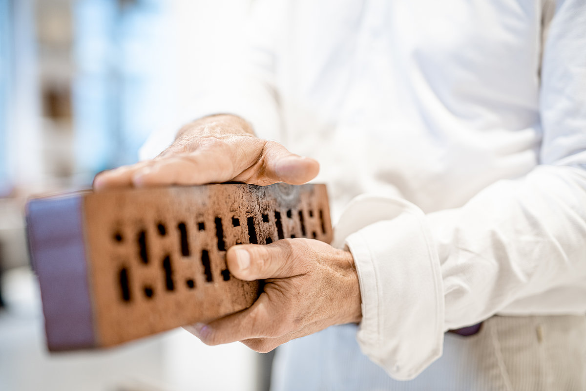 Hand on a long format clincer brick